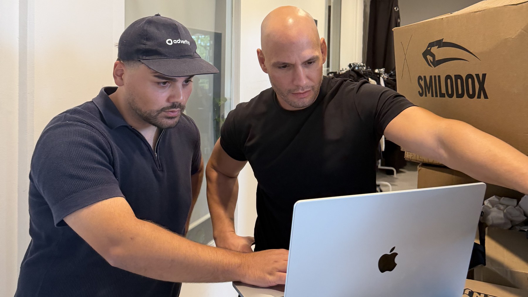 The Smilodox and Neosupps team at the laptop, next to a Smilodox carton